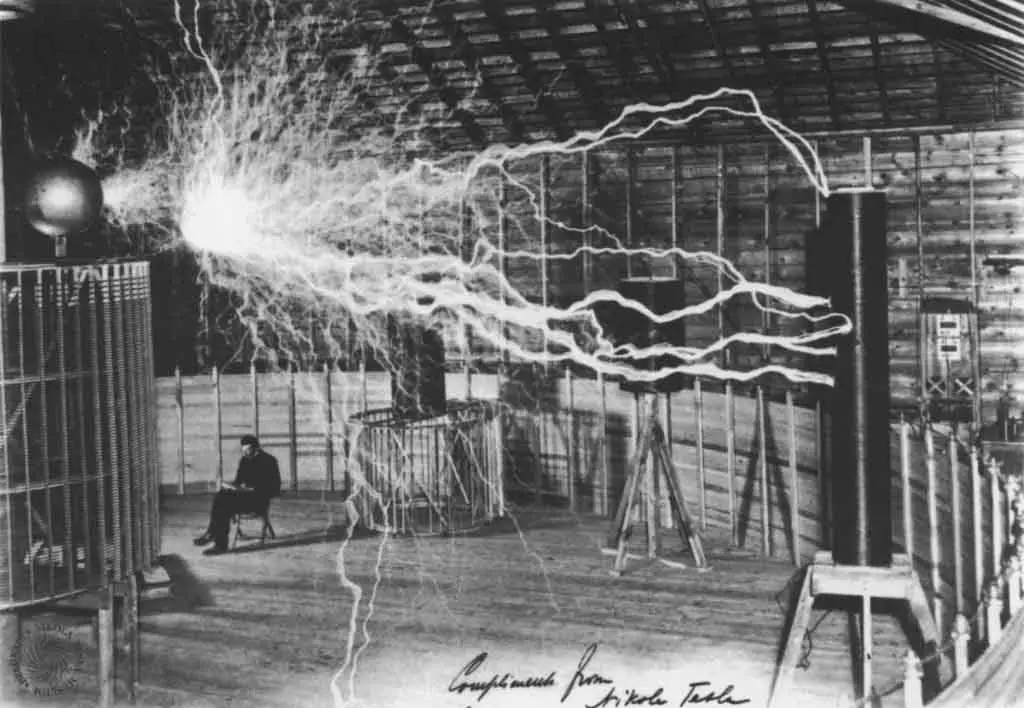 Tesla near his transmitter in Colorado Springs. The device was capable of transmitting millions of volts of electricity over great distances without wires. The image was taken in 1899.