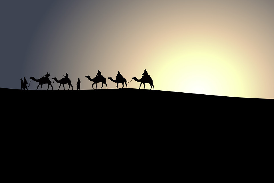 travellers in the dessert riding camels